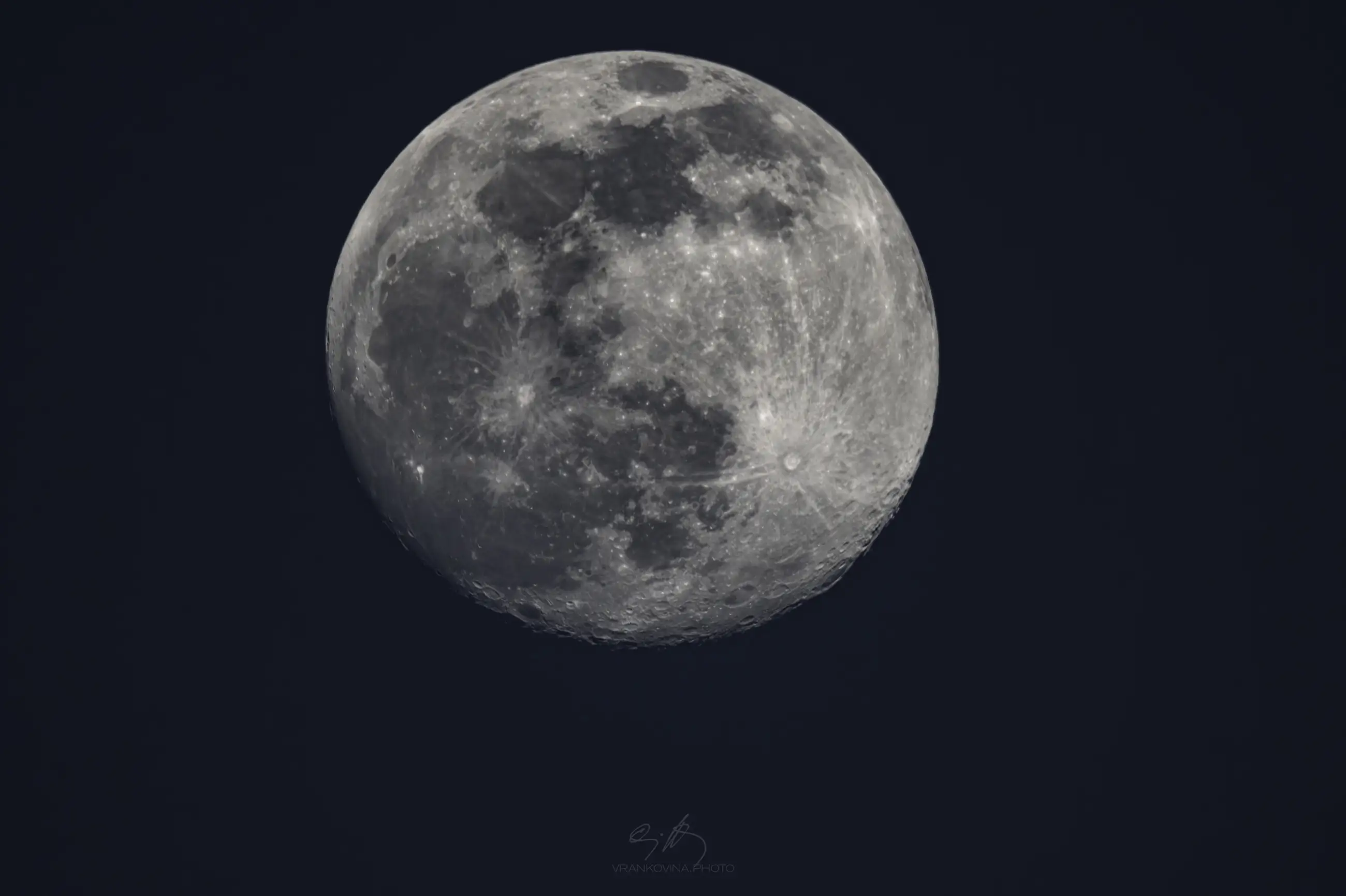 A detailed close-up image of a full moon against a dark night sky, showing craters and surface texture clearly.